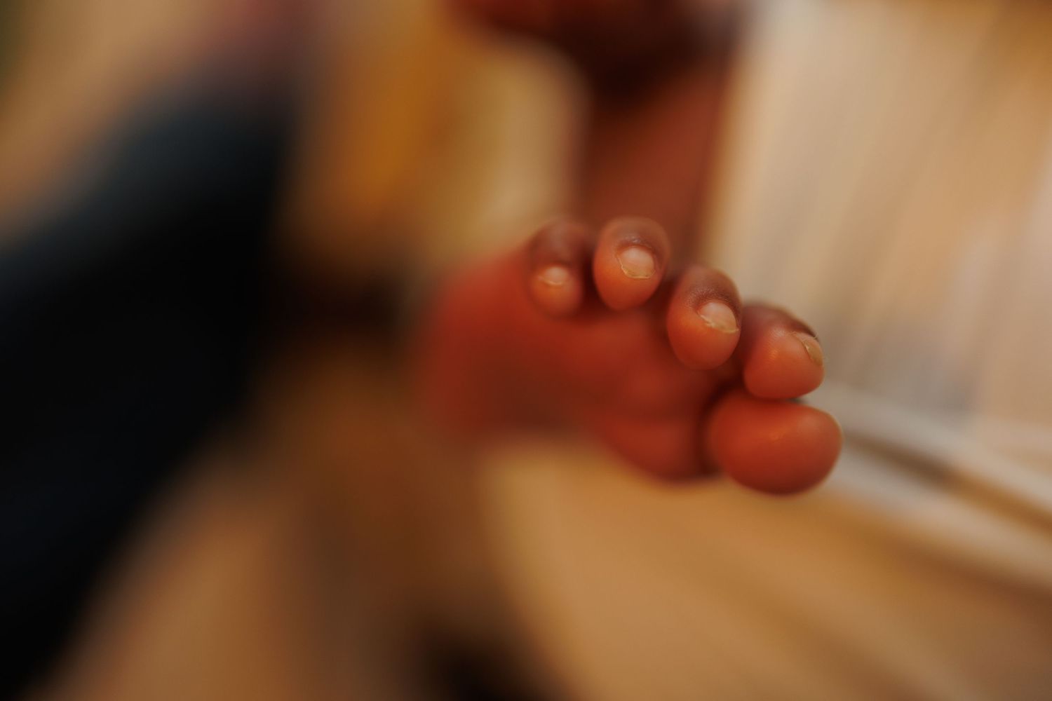 Close-up macro shot of small bare feet in soft focus with warm lighting and shallow depth of field.