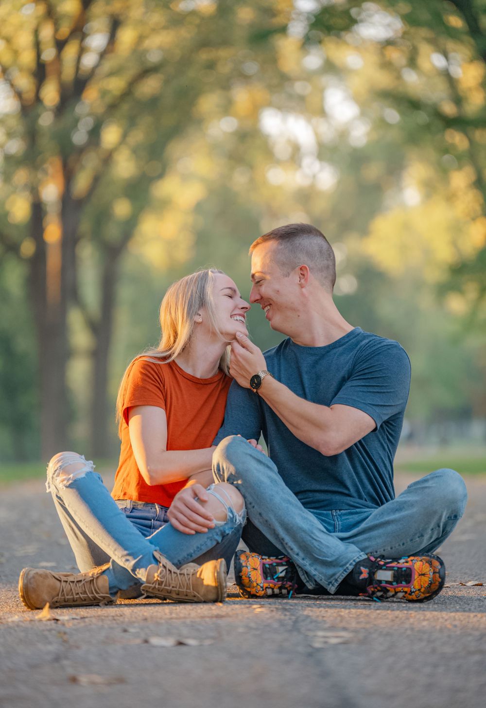 couple sitting on ground holding eachothers faces