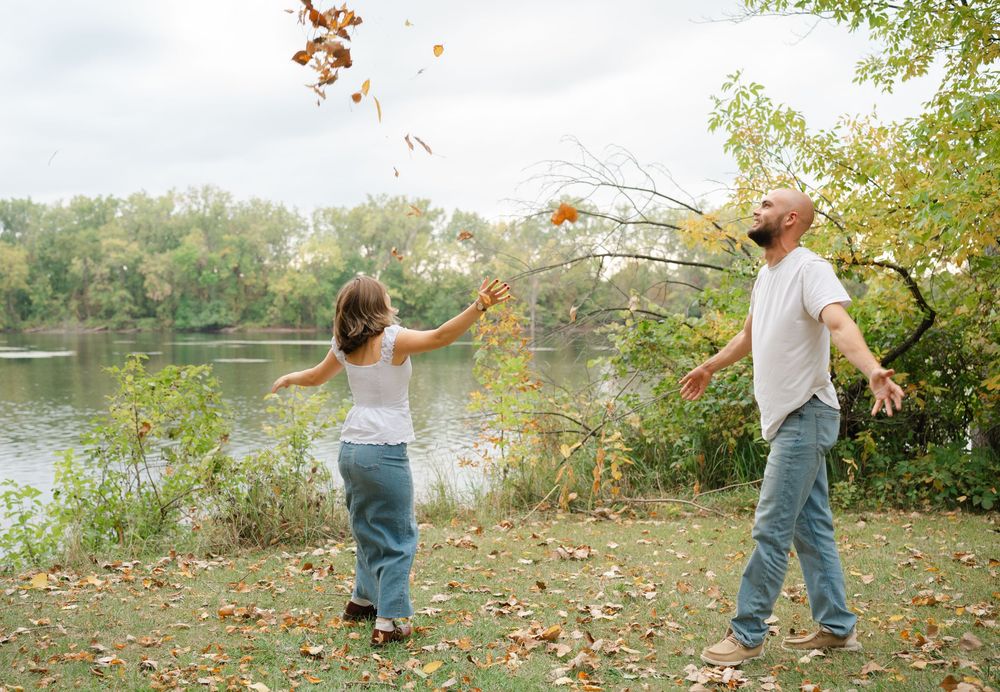couple throwing leaves in air having fun