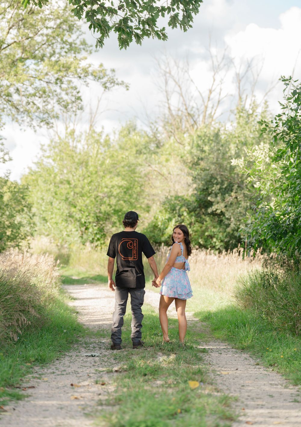 couple holding hands on path in the woods