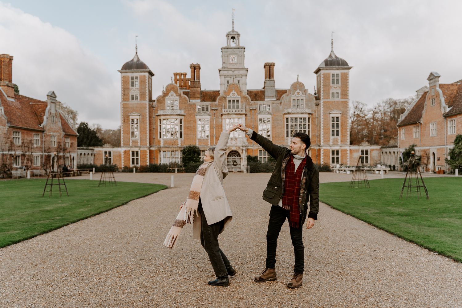 A couple are stood outside Blickling Hall in Norfolk and the lady is twirling under her husbands arm.