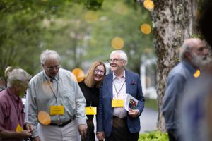 People mingling at an outdoor social event with bokeh lights in background.