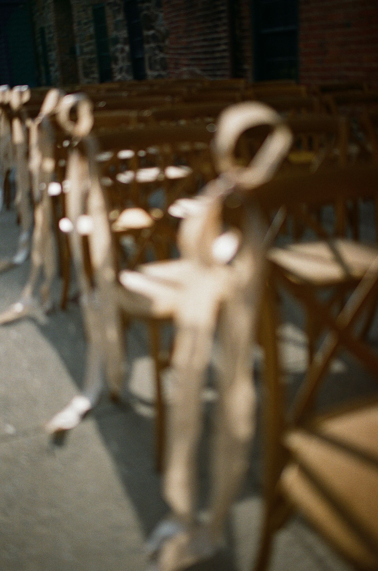 Blurred artistic view of wooden folding chairs with white fabric bows tied on their backs creating an elegant aisle display.