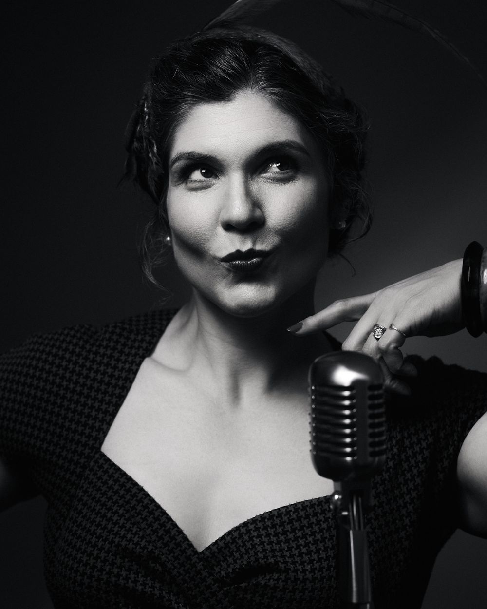 Performer in checkered neckline and finger-wave hair, pursing lips with vintage flair — all attitude, all atmosphere.
