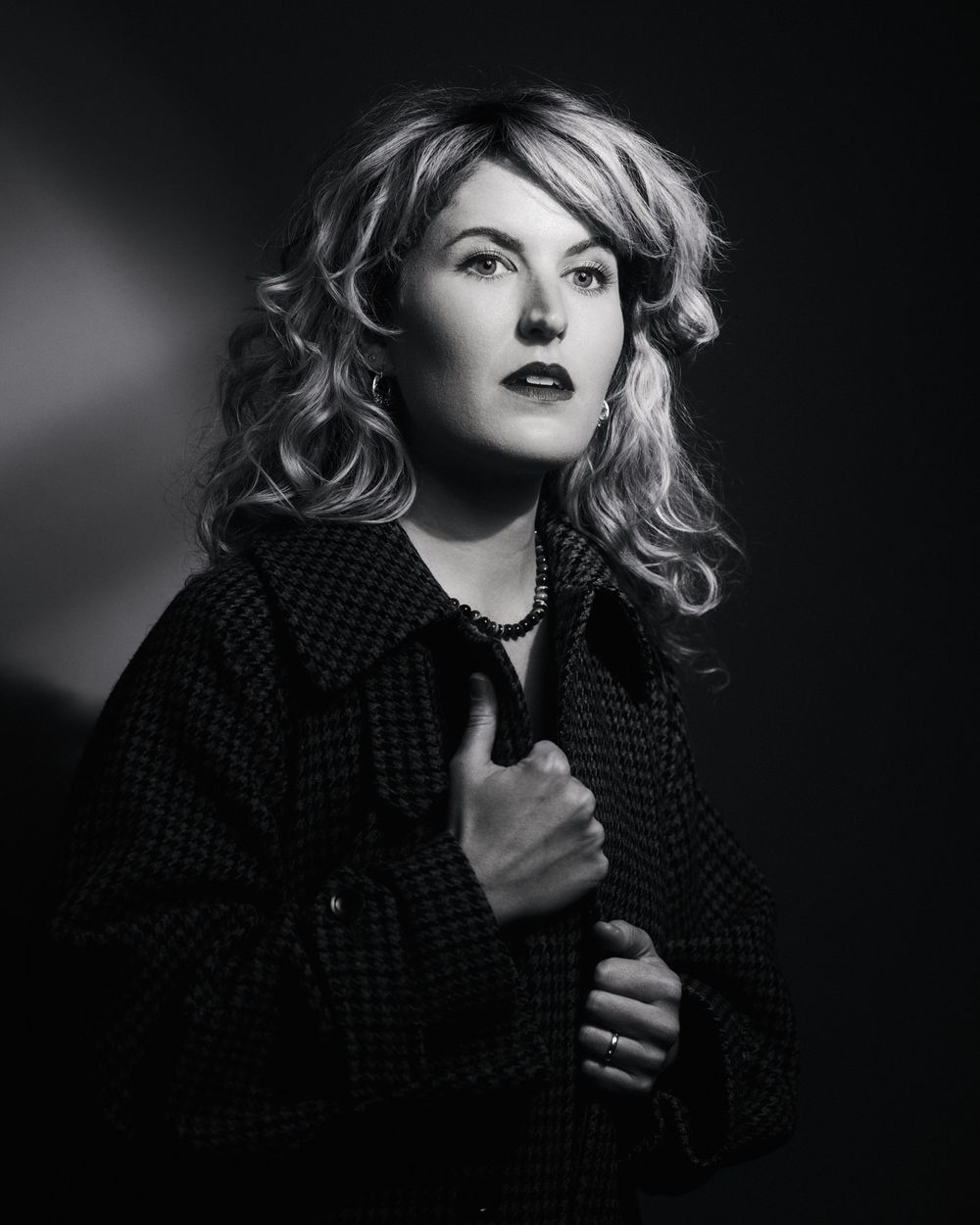 Old Hollywood softness and modern strength: blonde woman in coat, gazing past the frame in signature PML contrast.