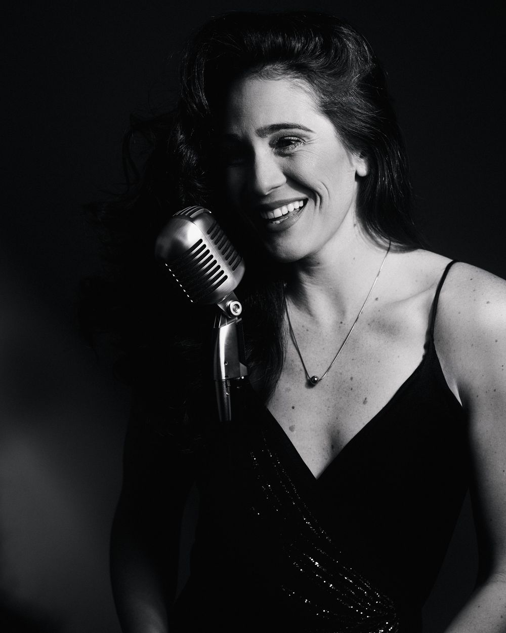 Singer mid-song, eyes alight with mischief, cast in the signature shadows of Postmodern Lightbox.