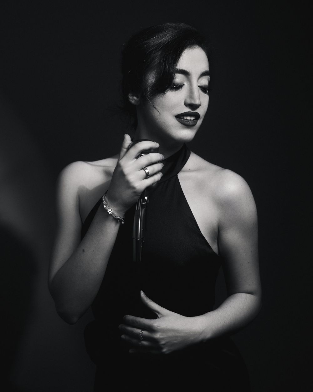 Classic Postmodern Lightbox lighting on a vocalist in halter dress, lost in the hush before the downbeat.