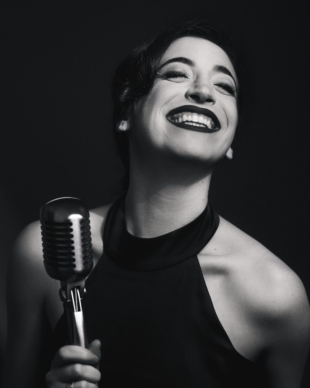 Performer in halter top beaming under hard key light, microphone in hand — energy and elegance meet in this PML moment.