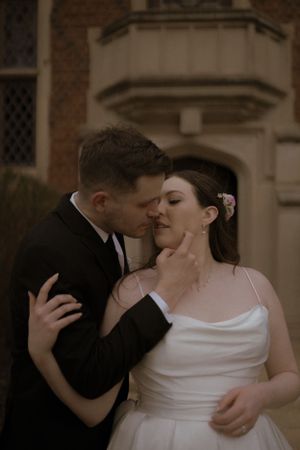 An intimate moment shared between a couple against a historic brick building backdrop.