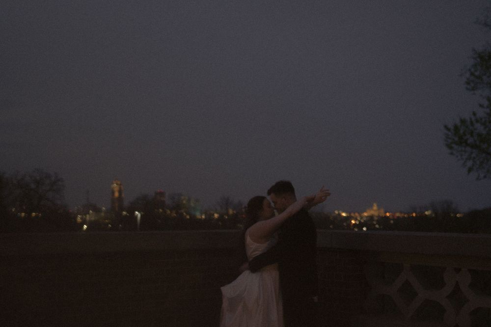 A silhouetted couple embraces against a city skyline at dusk.