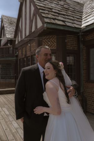 A heartwarming wedding moment captured on a rustic wooden deck with Tudor-style architecture.