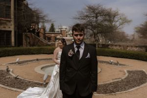 A dramatic wedding photo with couple posing in a circular garden courtyard.