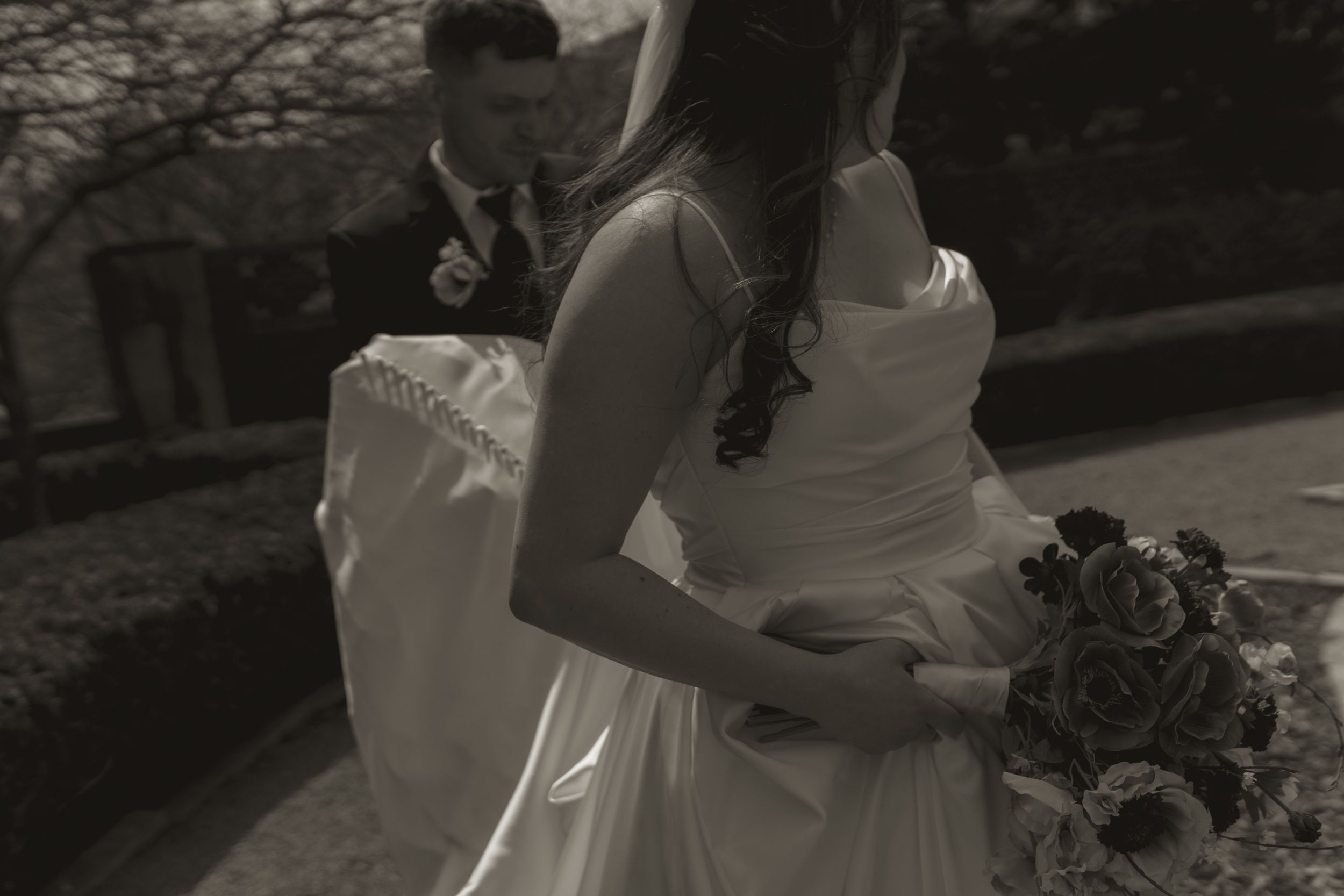 Couple embraces outdoors in romantic black and white photography.