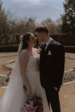 A romantic wedding portrait in a garden with the couple sharing an intimate moment.