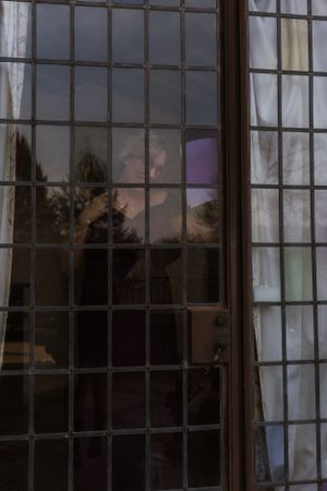 Artistic view through a gridded window pane creating a moody silhouette effect.