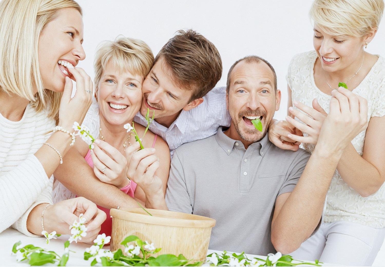 A laughing group of people enjoying fresh salad and healthy food together around a table.