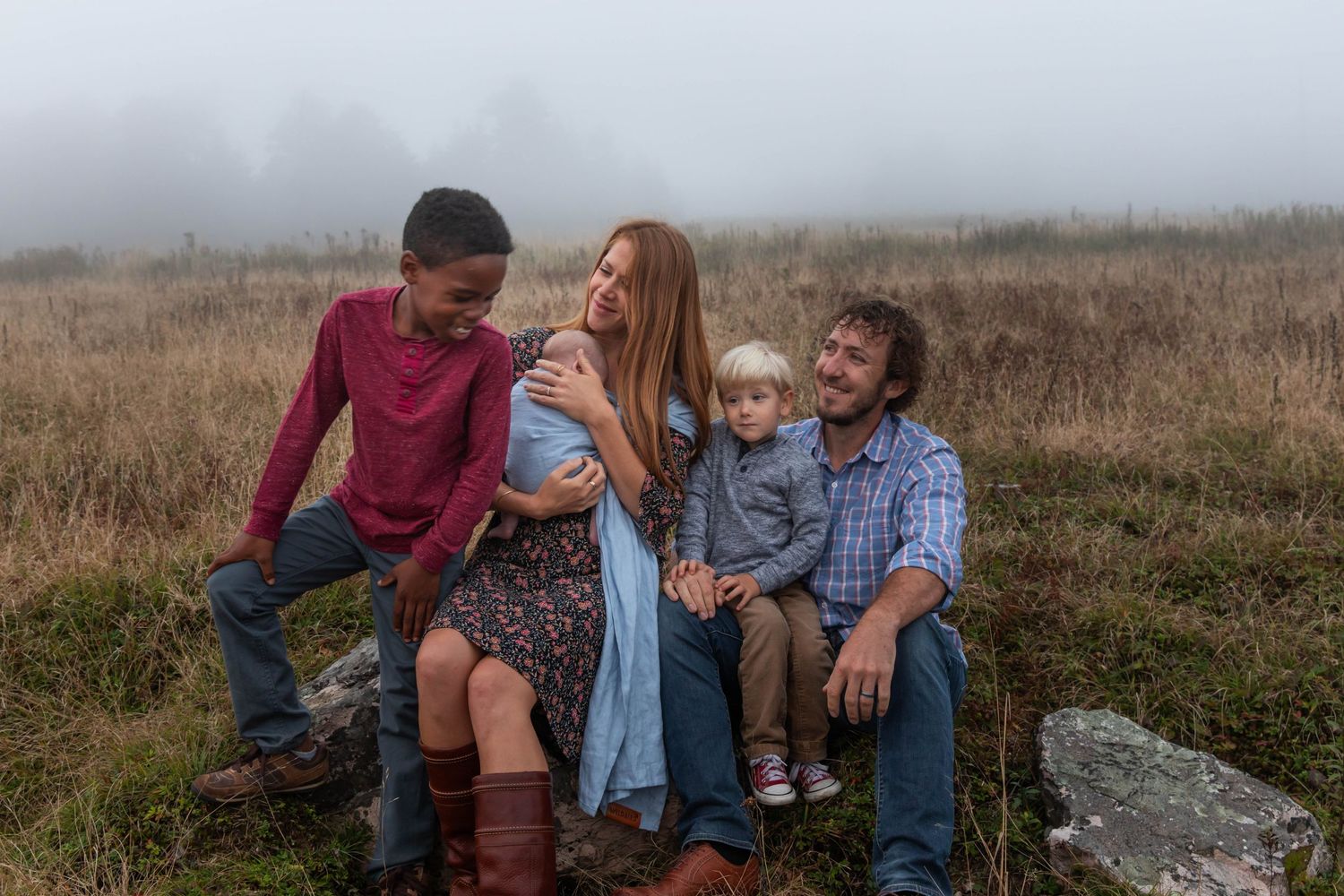 Image of a family sitting in a field on a mountaintop during family photos on a mountain in the fog