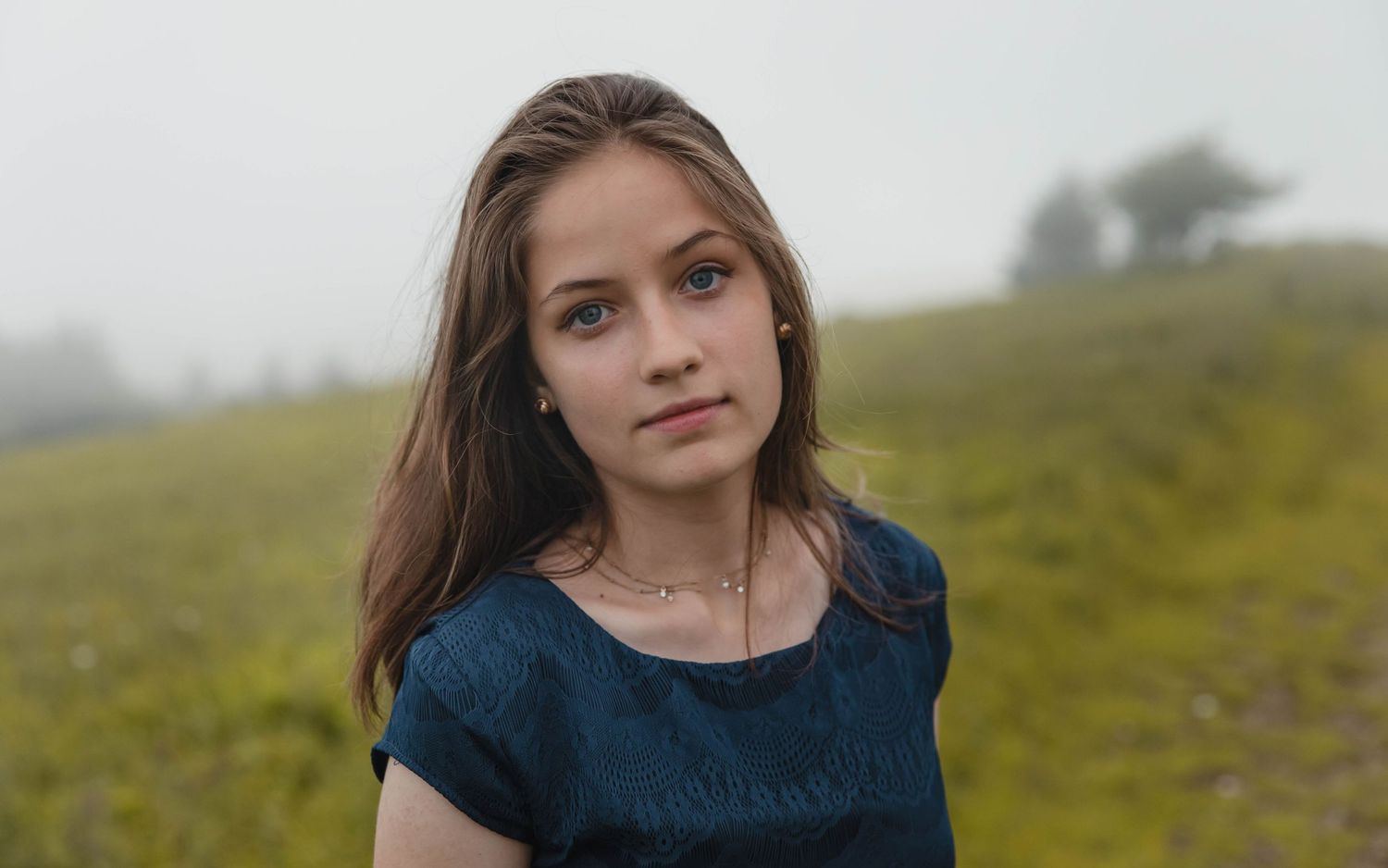 Photo of a girl in a blue dress on a foggy mountain