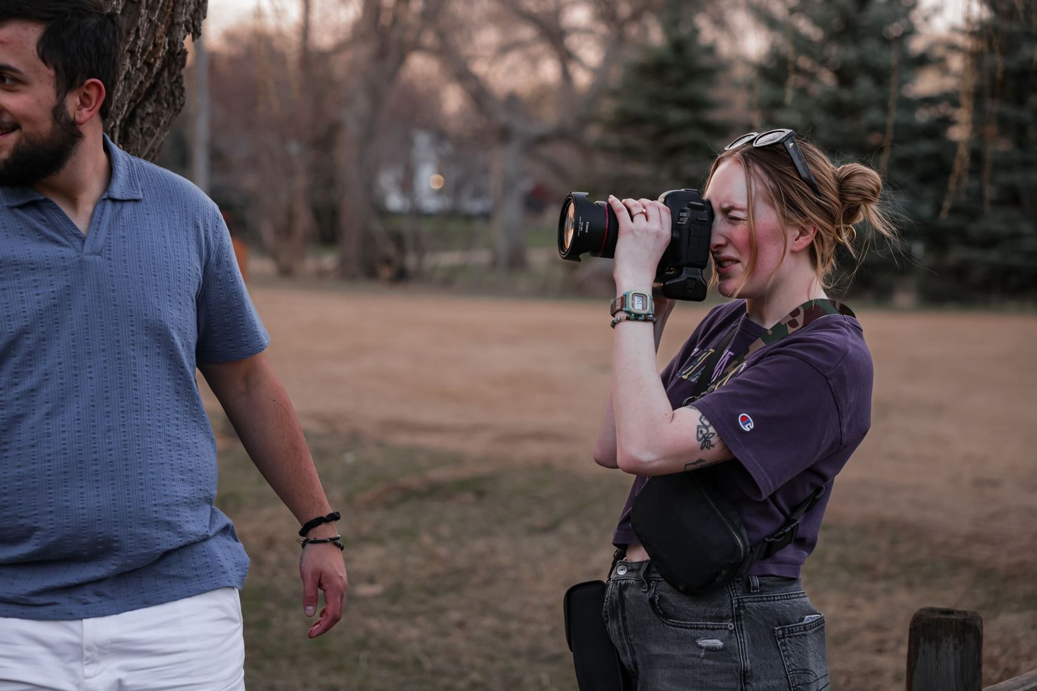 Photographer crouches down to take photos outdoors during golden hour.