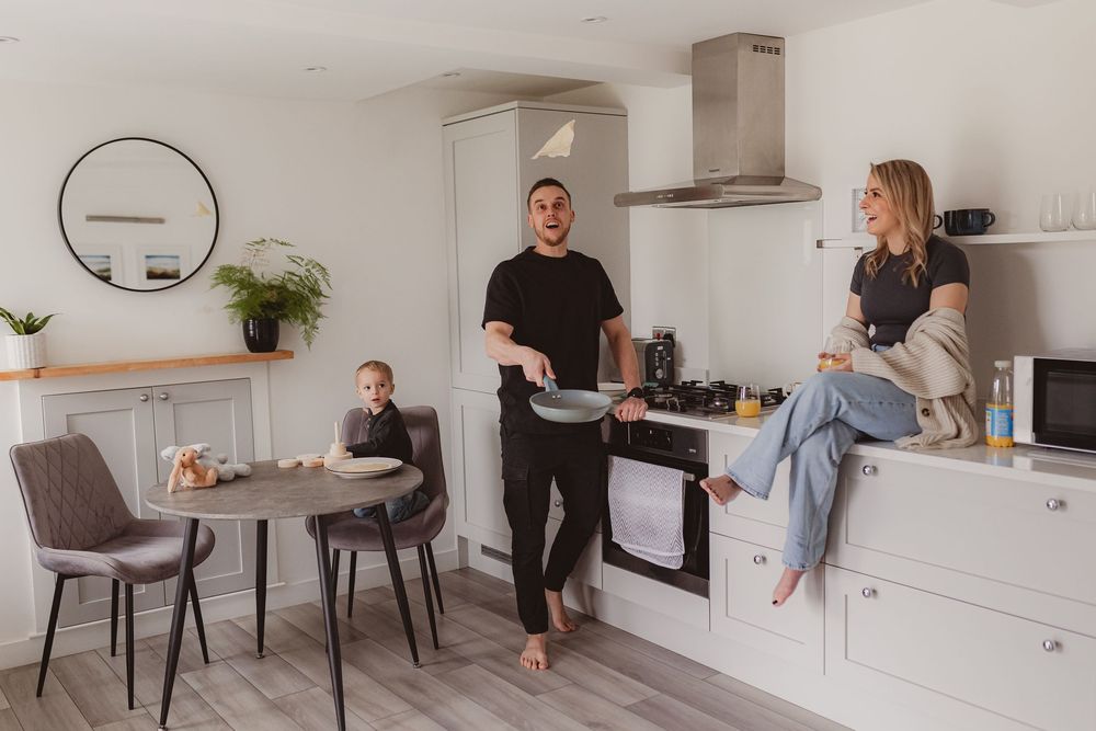 Cheerful family in bright modern kitchen, father cooking pancakes while mother and child enjoy the morning.