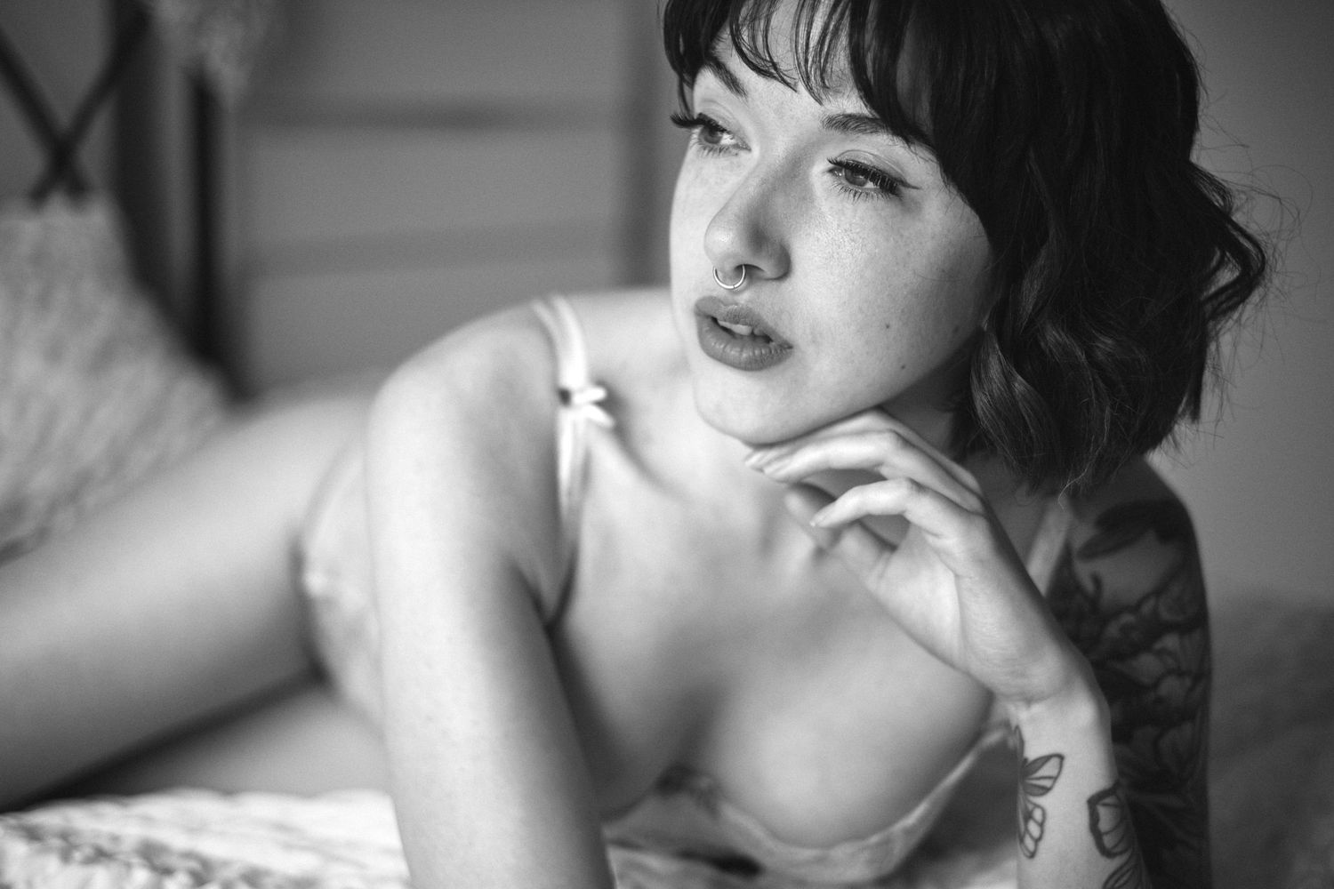 empowering boudoir photoshoot of a woman. black and white photo of a woman with soft lighting, she is posing with an arm above her head