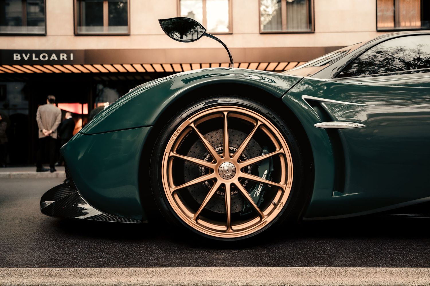 Close-up of a luxury sports car's copper-colored wheel and green metallic paint outside Bulgari store. Mtlshutter photography