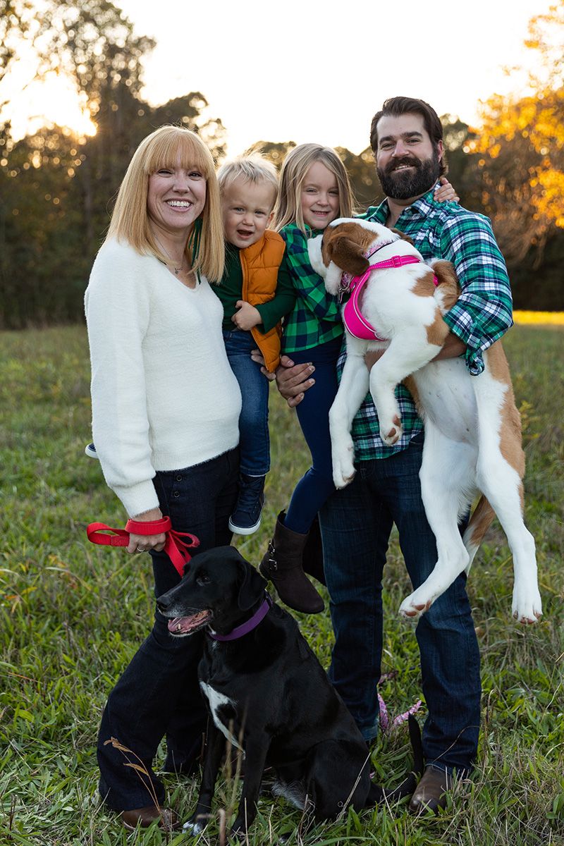 Family portrait with two dogs in a sunny autumn field.