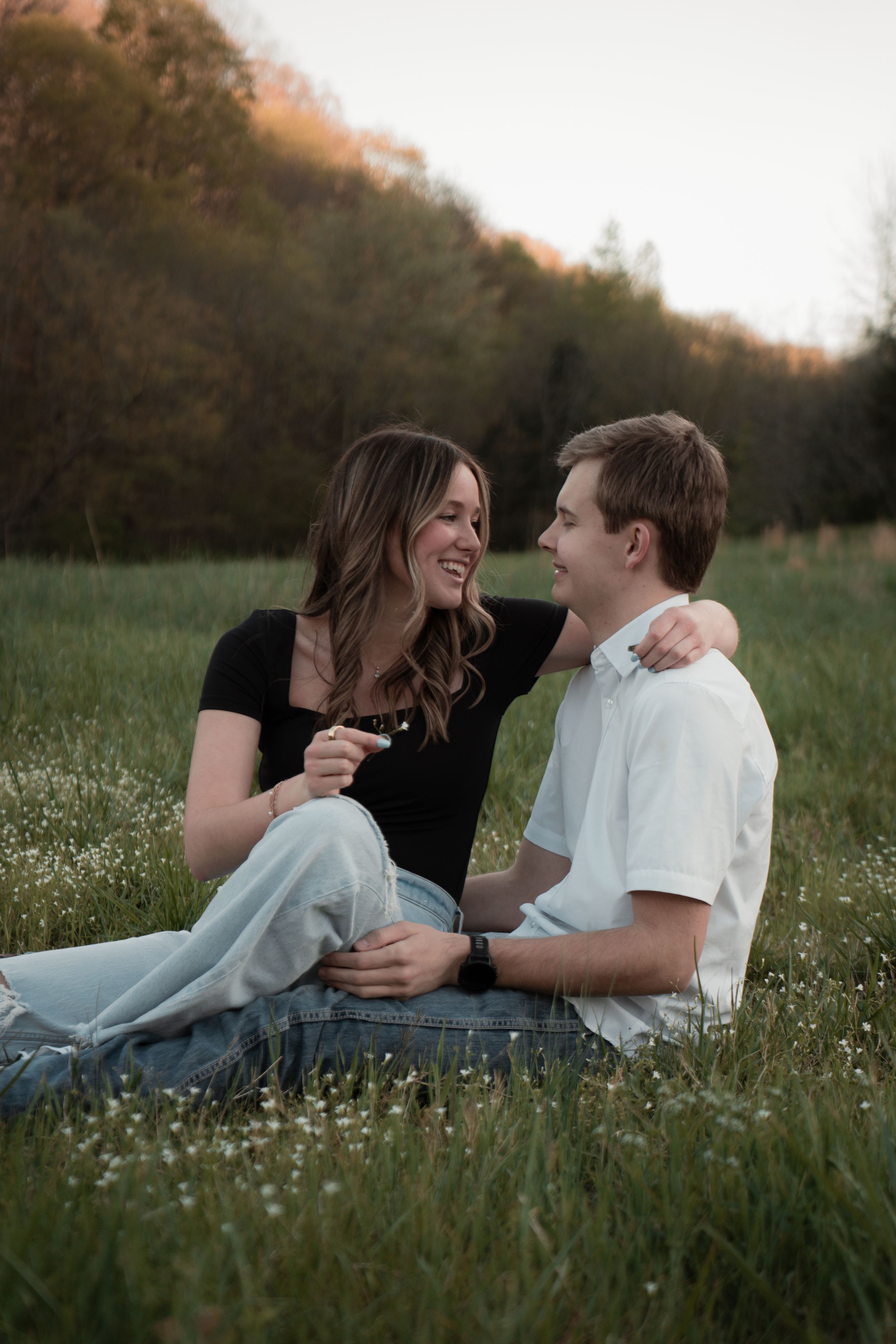 A couple shares a romantic moment while lying in a wildflower meadow at sunset.