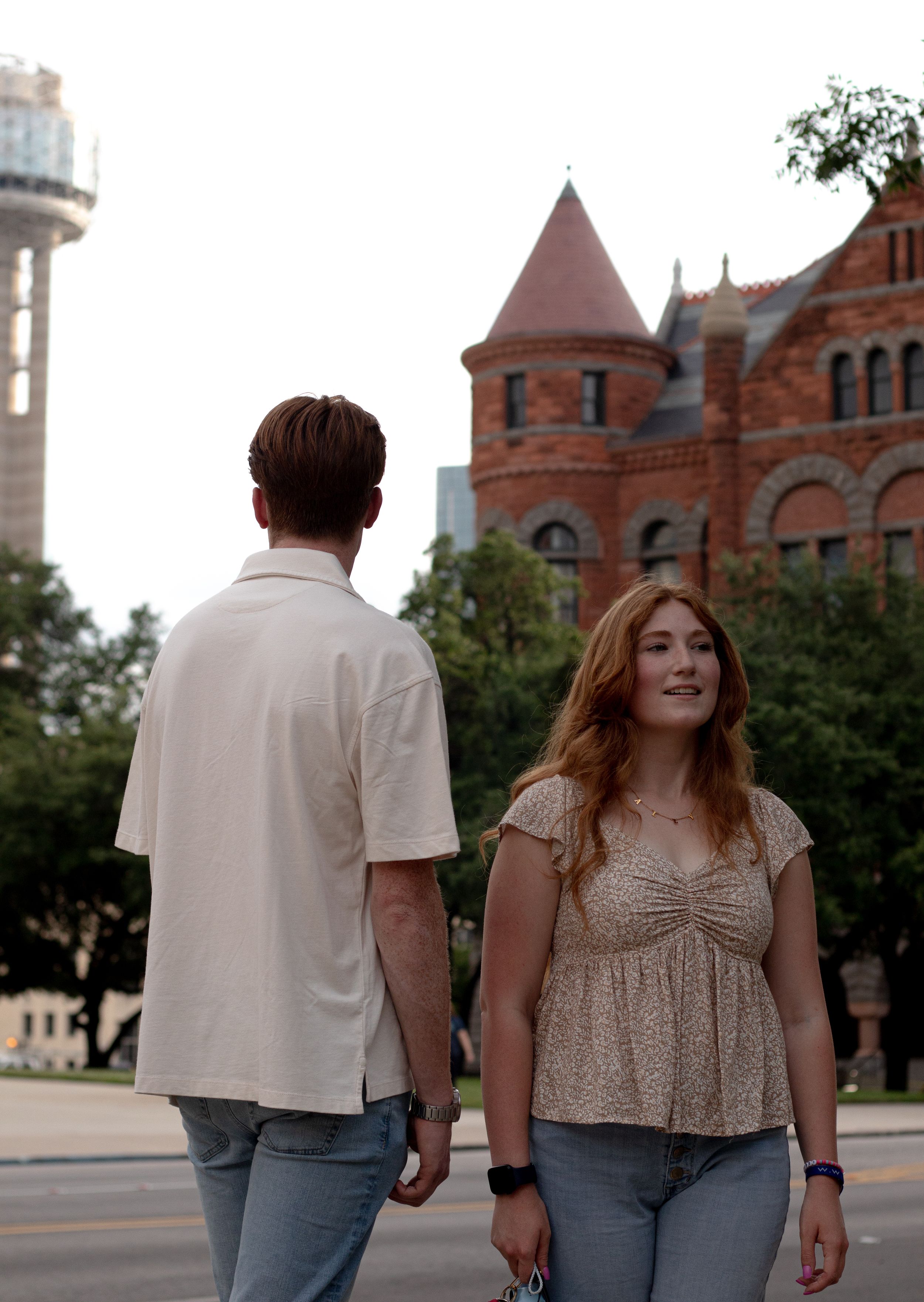 Couple walking together outside historic red brick buildings with turrets.