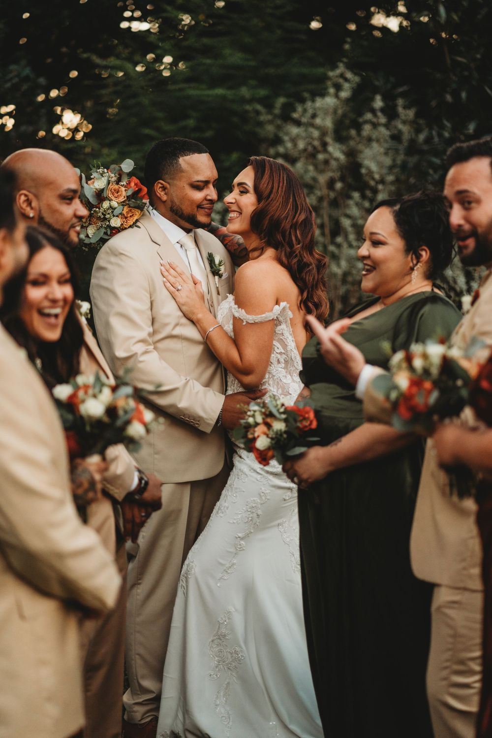 Wedding party celebrates joyfully with the newlyweds during outdoor ceremony.