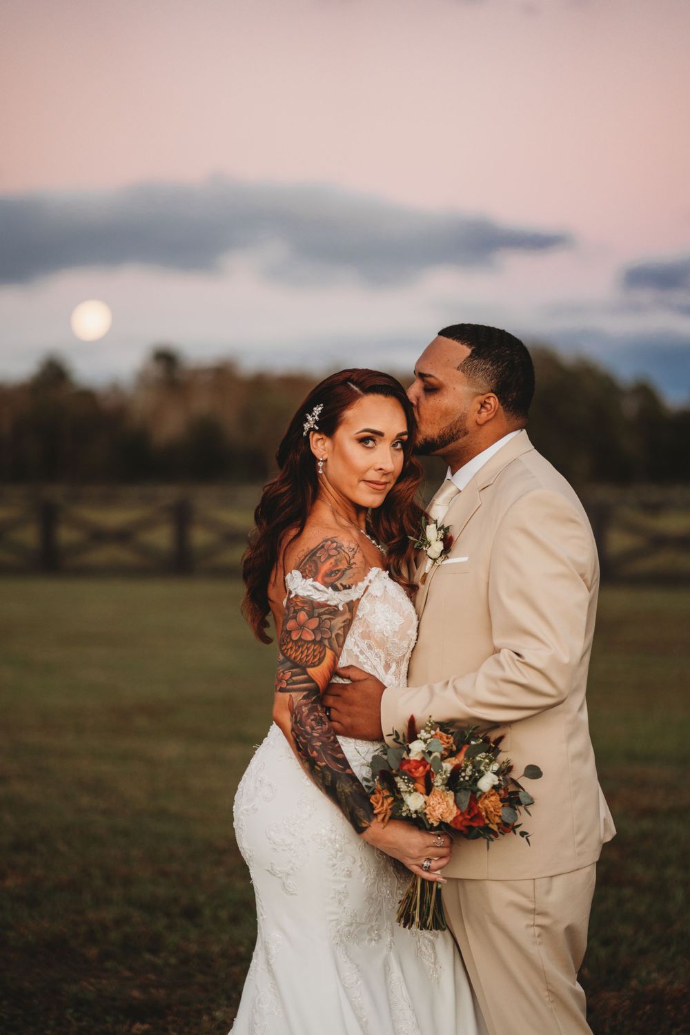 Romantic sunset wedding portrait with full moon rising in background.