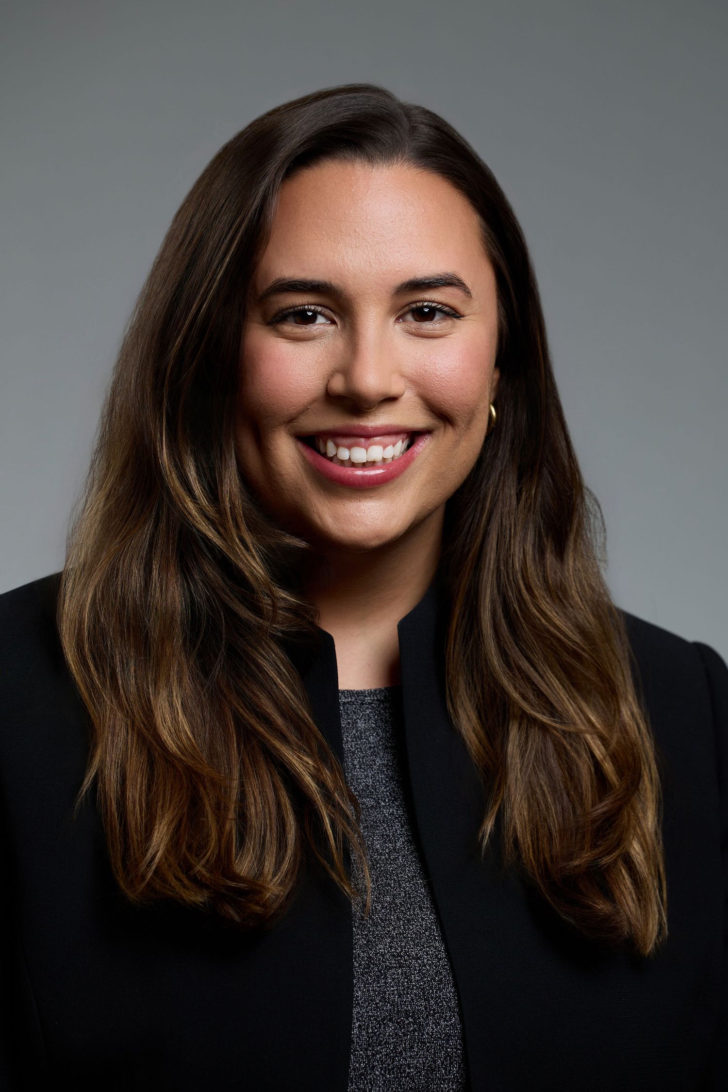 Professional headshot of someone with long brown hair wearing black blazer.