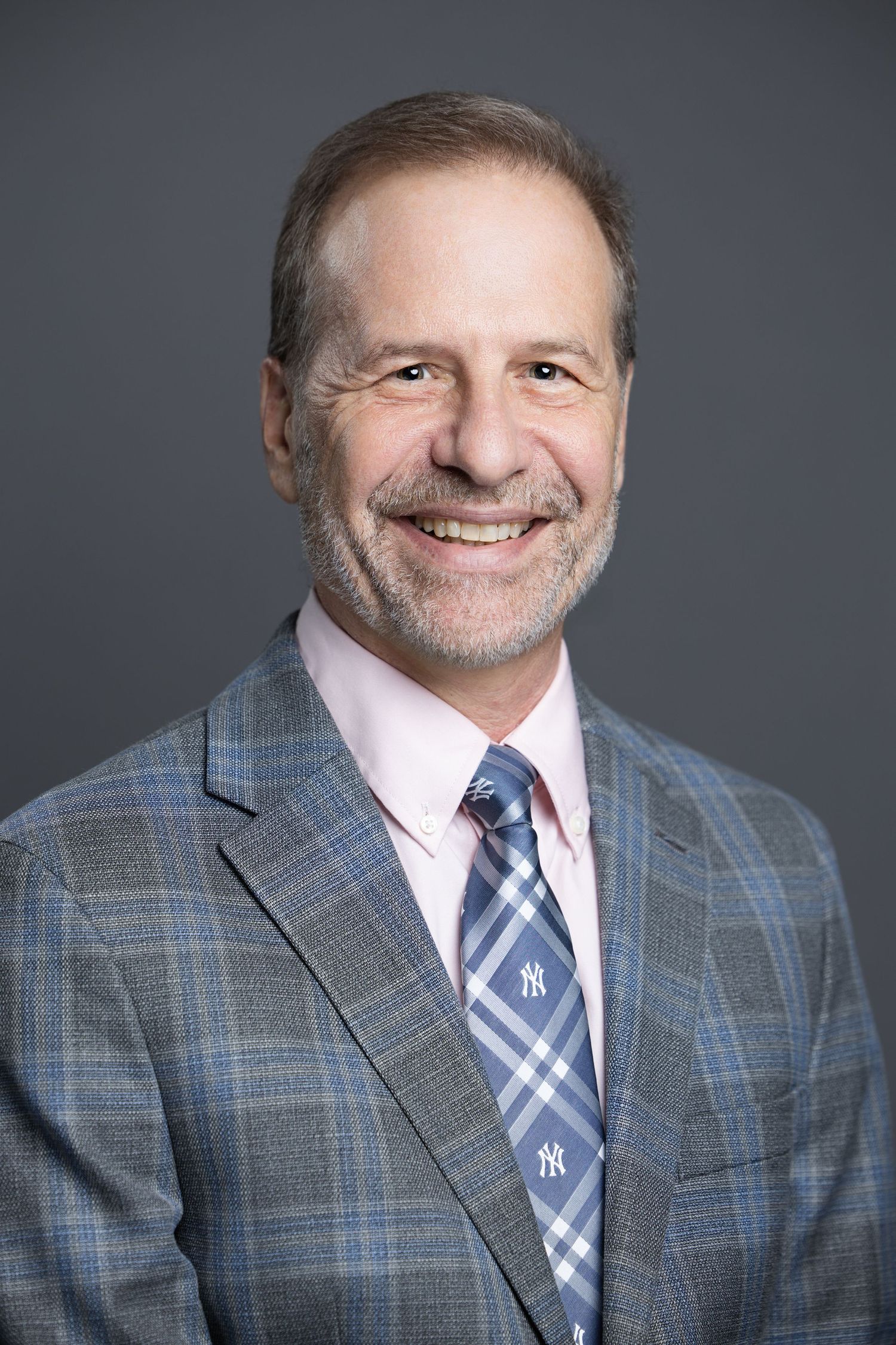 Professional headshot of person wearing plaid suit jacket and striped tie.