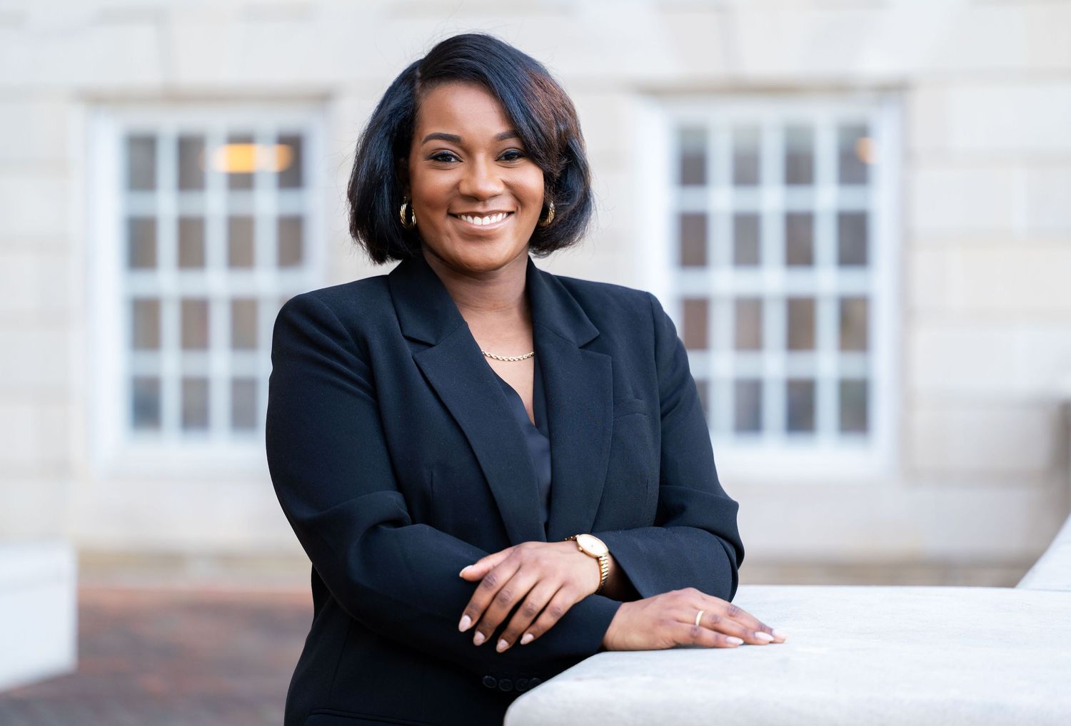Business professional portraits featuring person in dark suit against light building exterior.