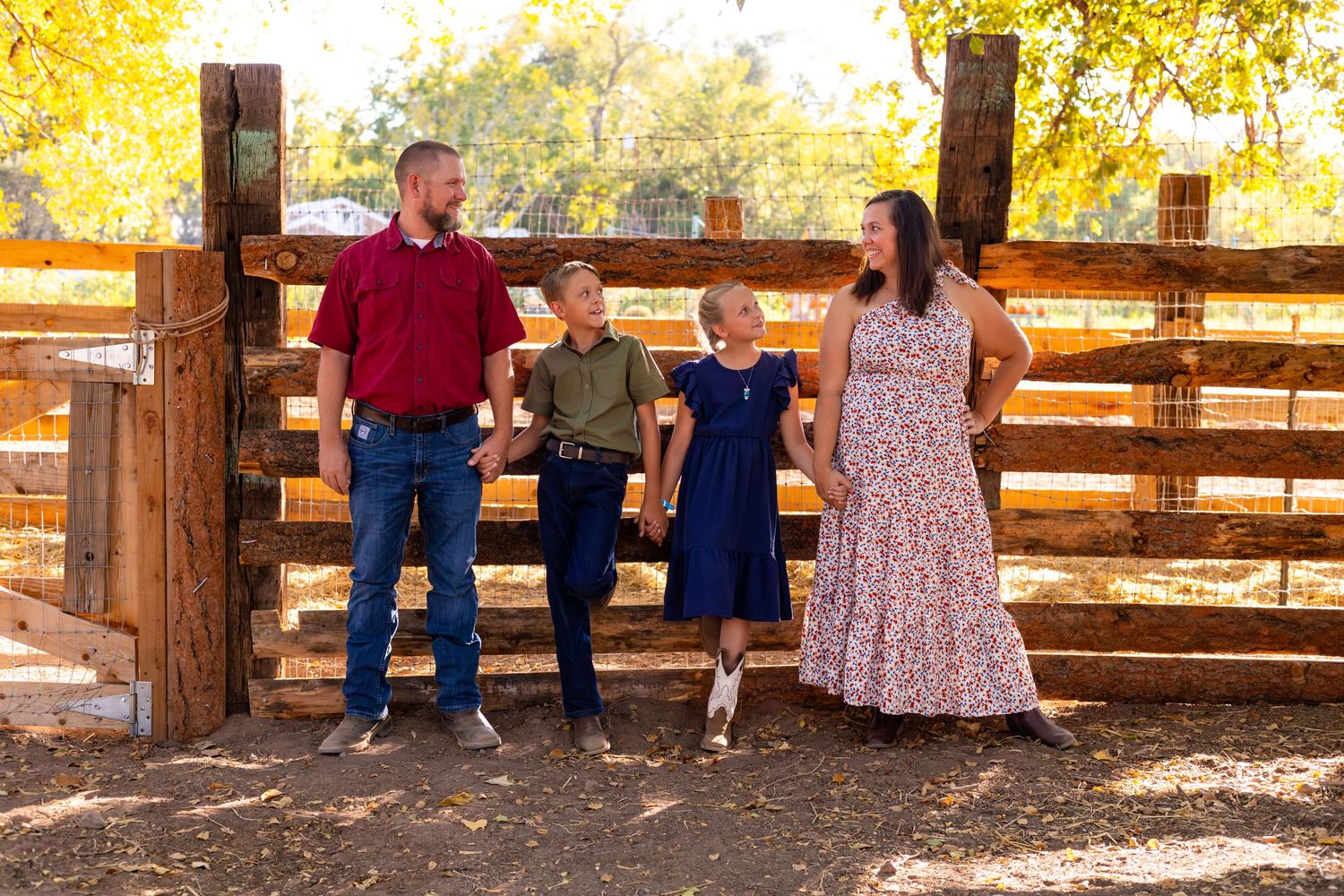 Family standing together by a rustic wooden fence during an autumn photoshoot.