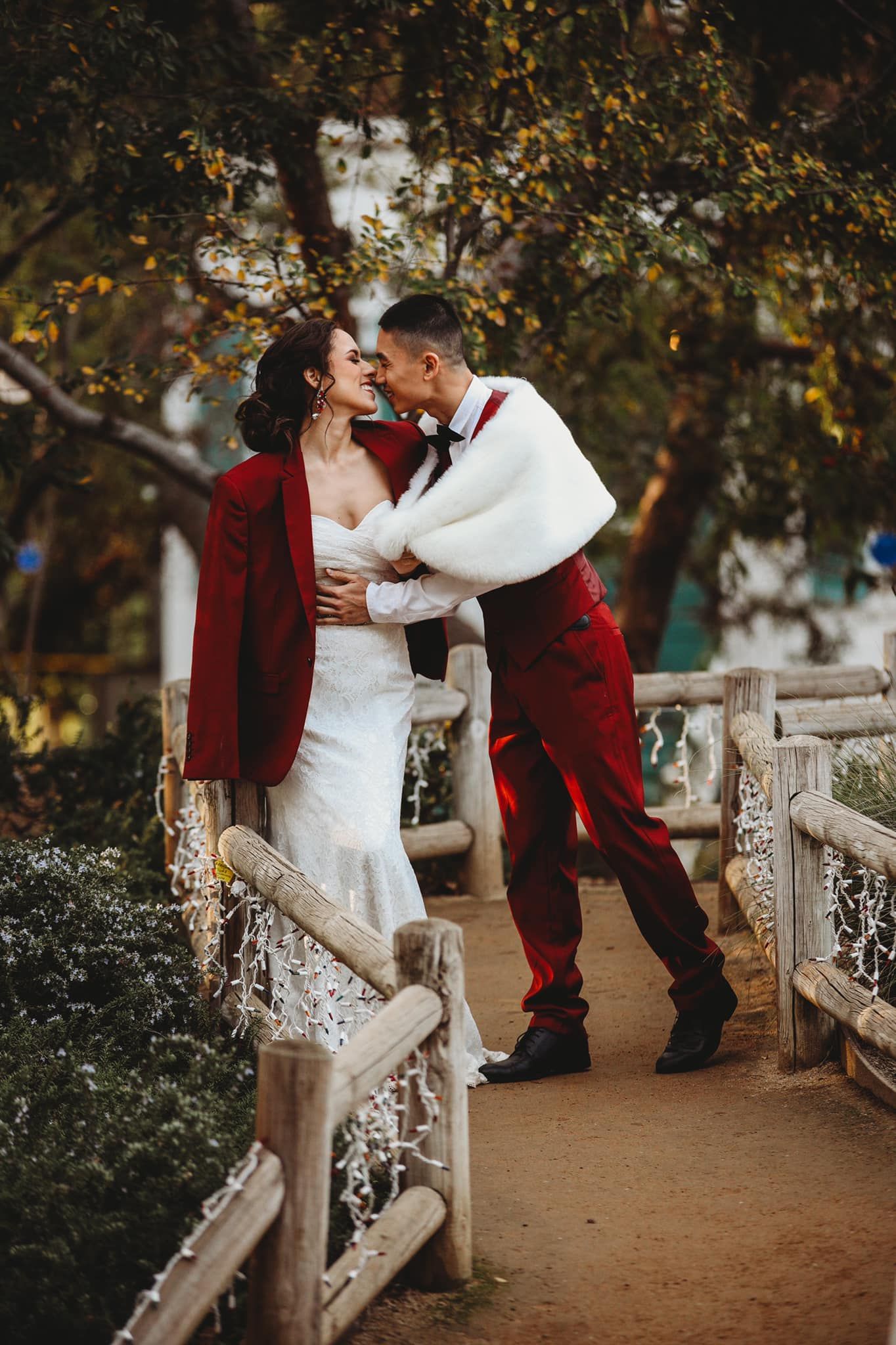 Romantic wedding couple embracing on bridge decorated with lights.