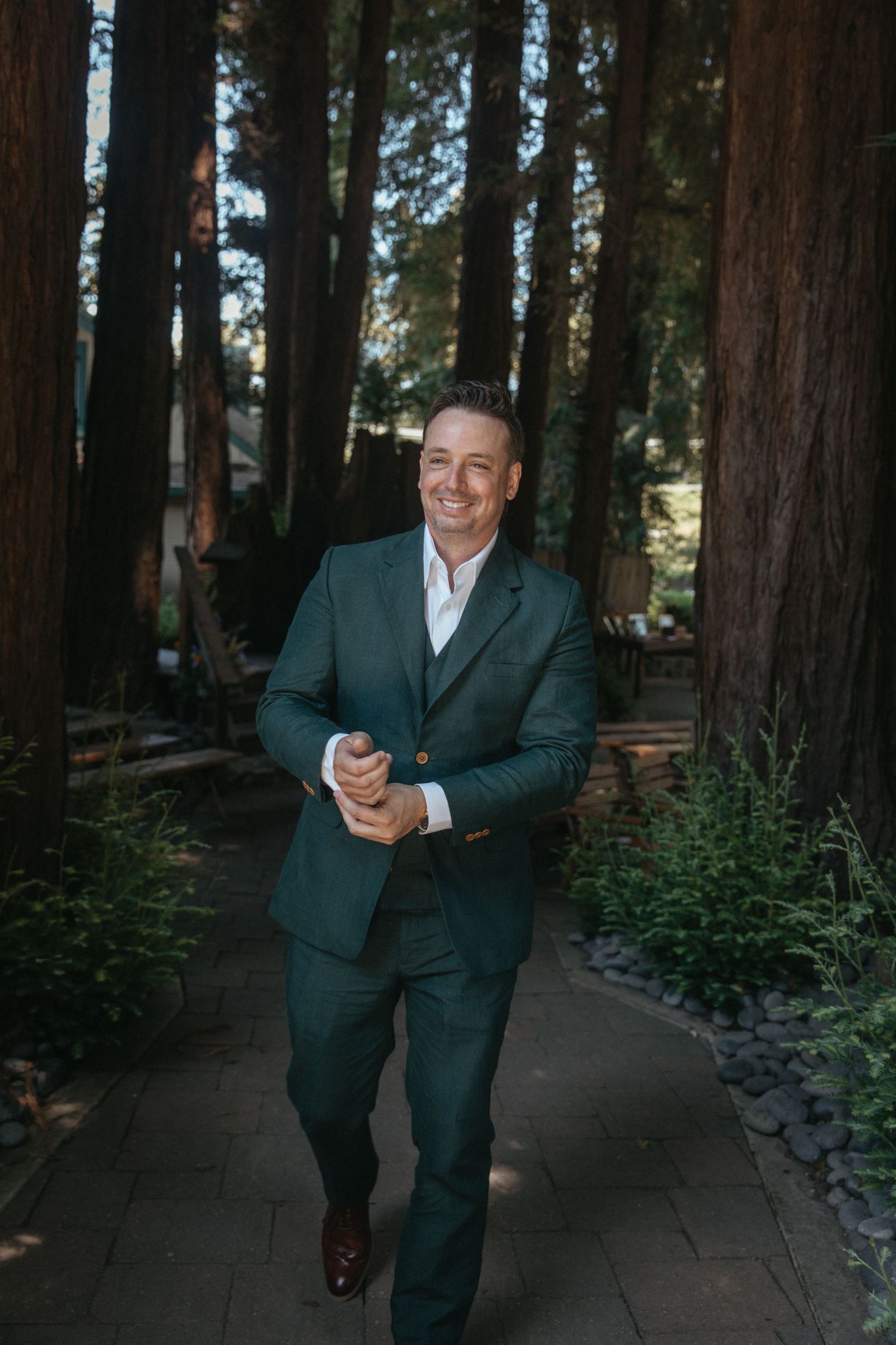 A color photo series showing a person in a formal dark suit posing against a backdrop of tall trees and forest paths.