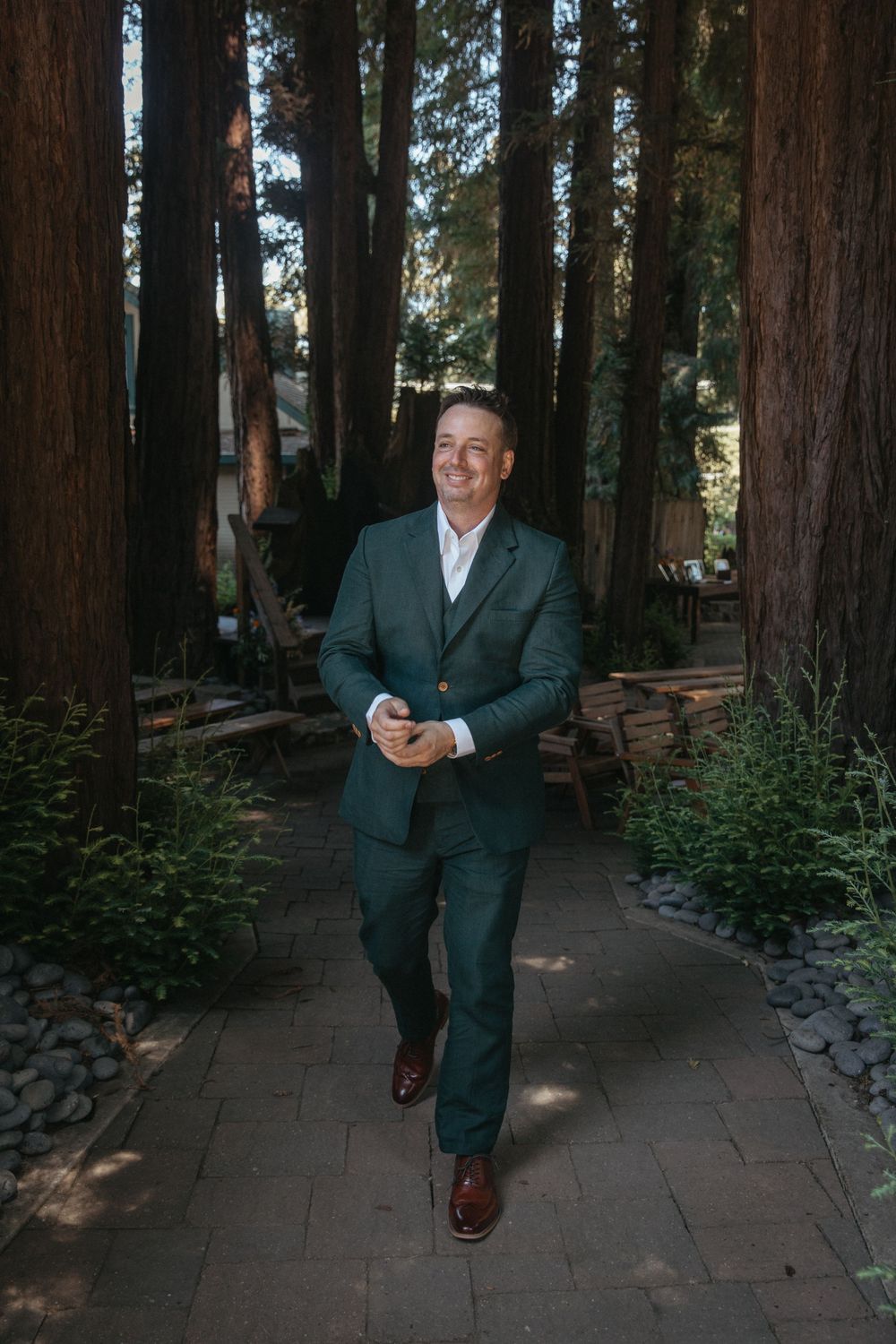 A sequence of photos showing a person in a dark suit walking through a redwood forest setting on a stone path.