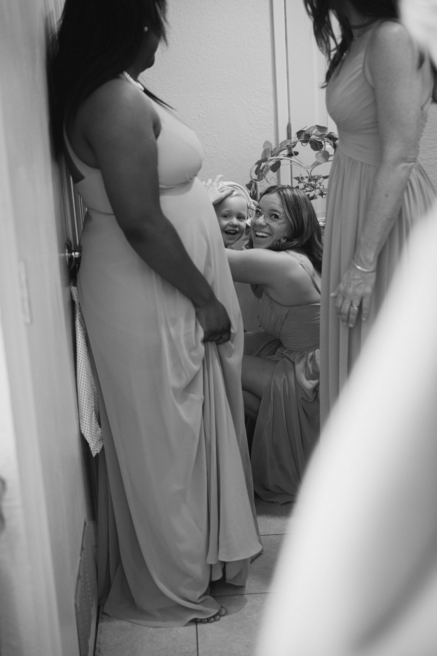 Bridesmaids in light colored dresses share emotional moments while getting ready for a wedding ceremony.