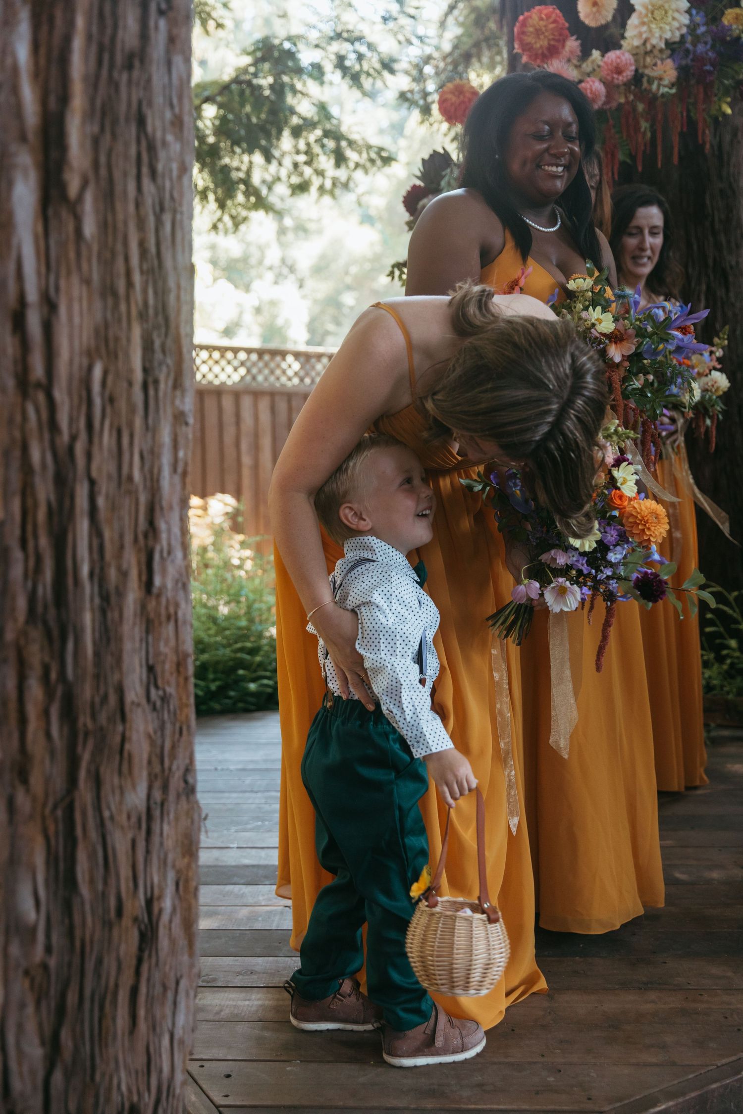 A candid moment at a wedding with bridesmaids in yellow dresses and a small child playing among them.