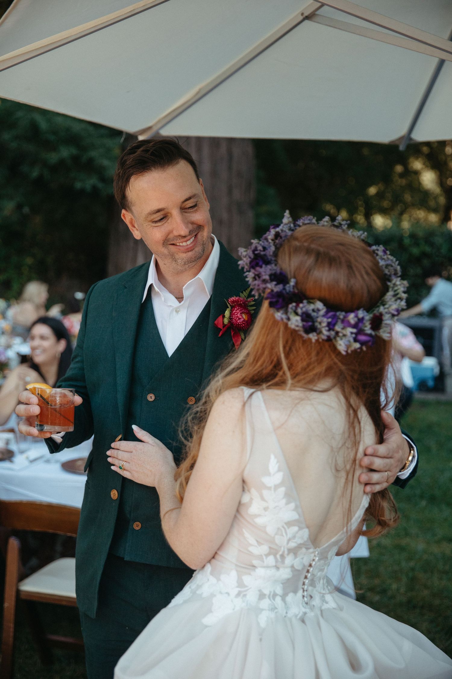 Couple shares intimate moments under a white tent during outdoor wedding reception.
