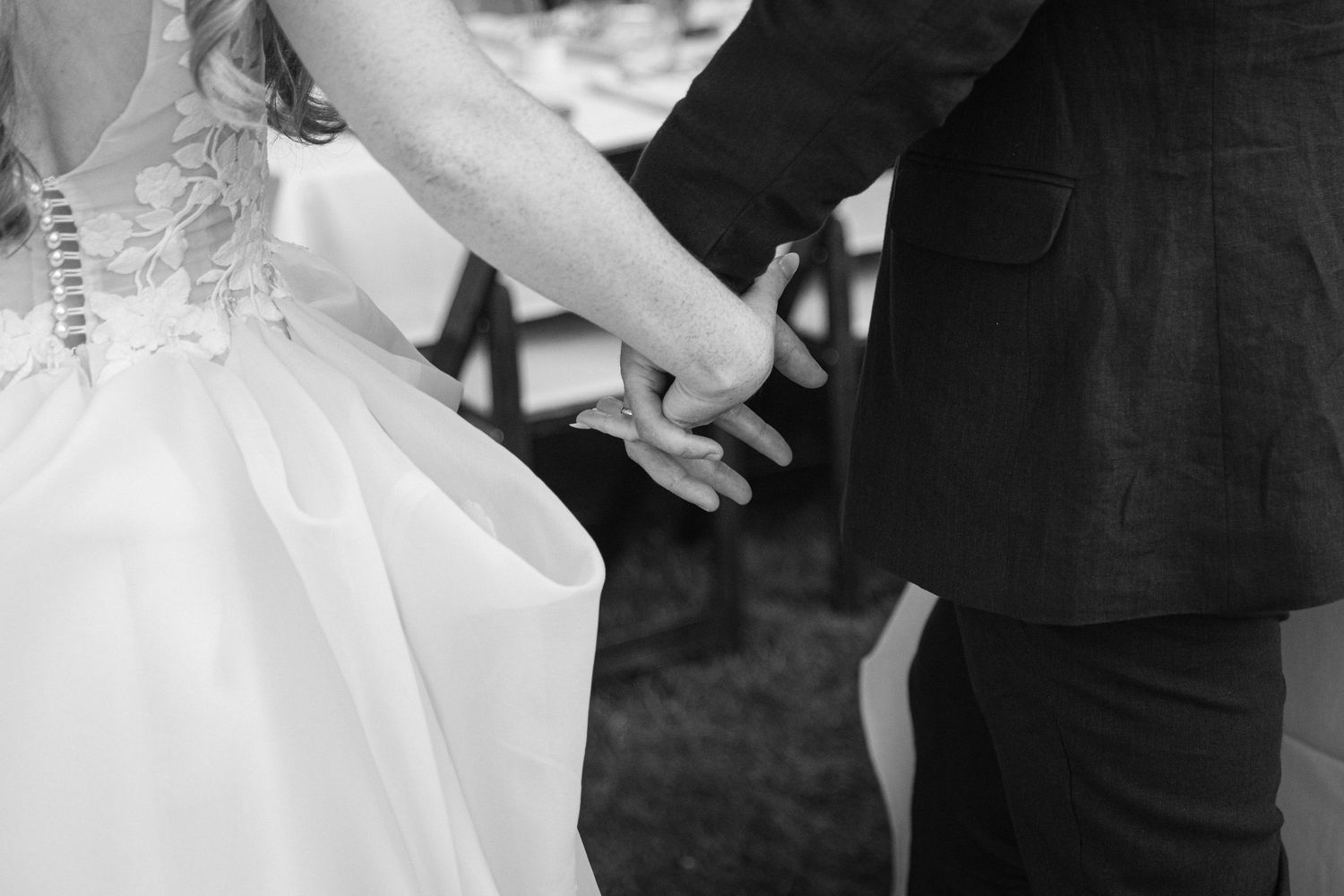 Black and white close-up of a couple holding hands at their wedding ceremony.