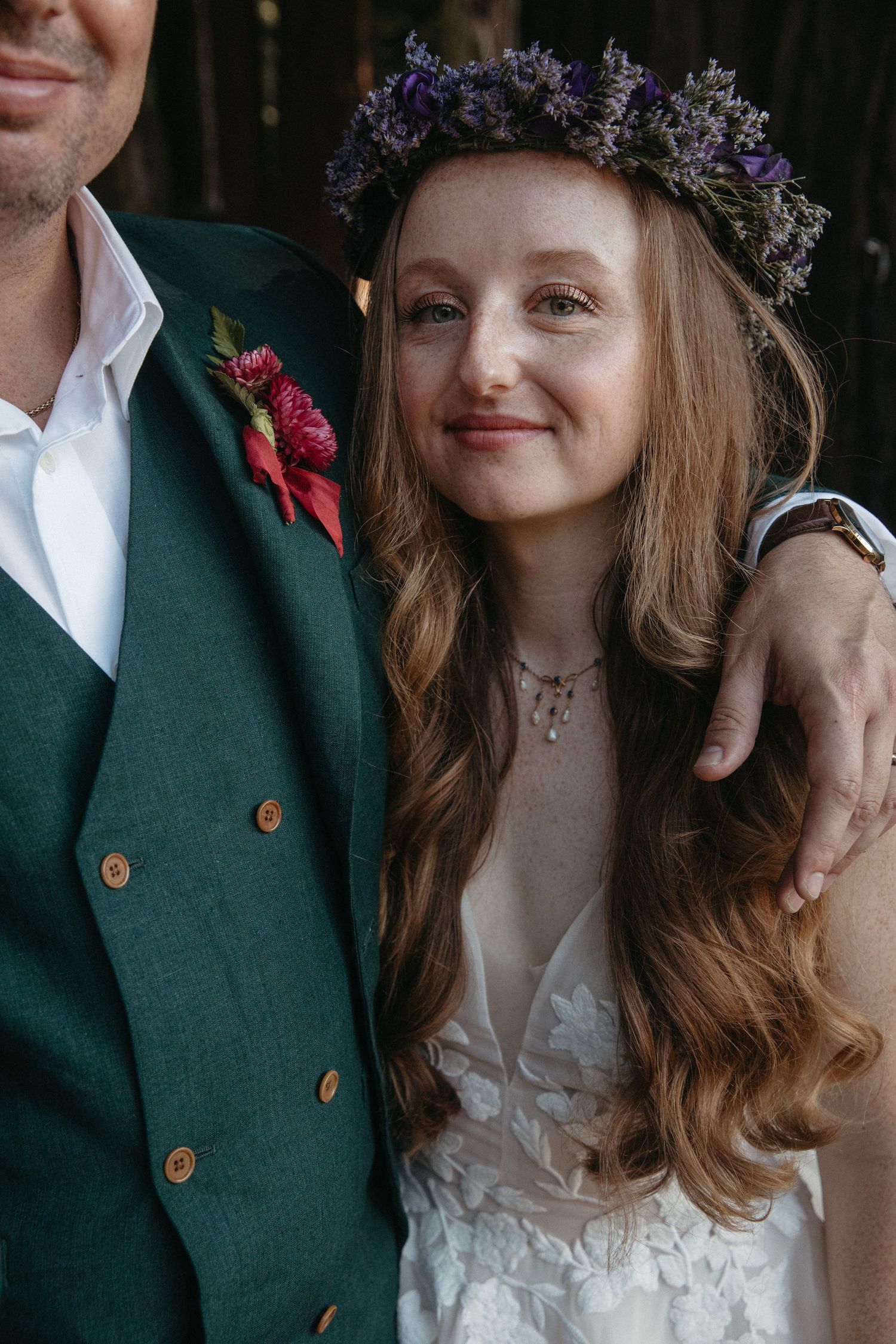 Close-up wedding portrait showing a couple with the bride wearing a floral crown and white dress.
