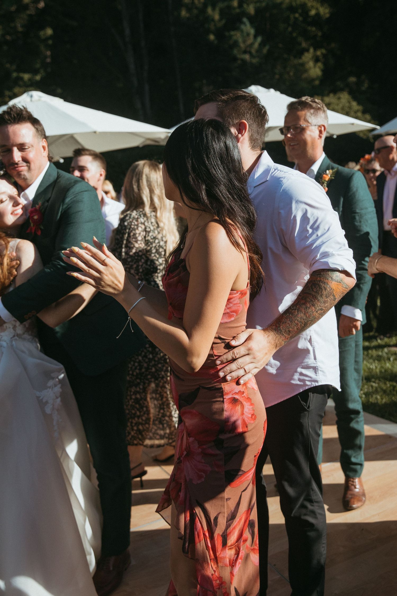 Wedding guests dancing together at an outdoor reception venue with white tents.