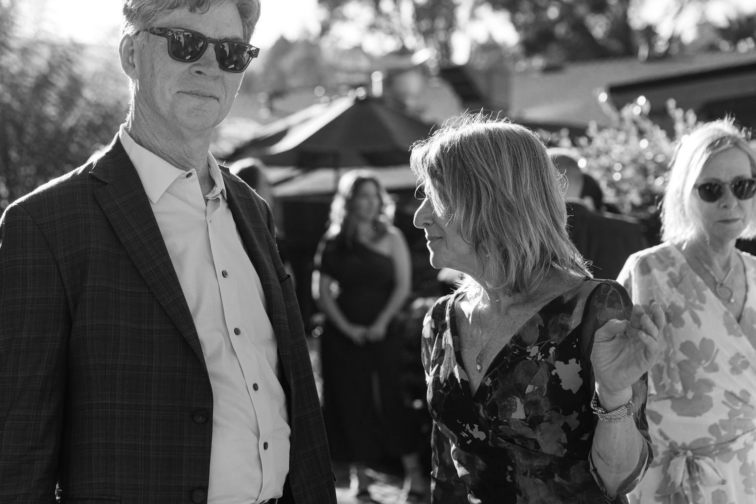 Black and white candid shots of wedding guests enjoying themselves at an outdoor celebration.
