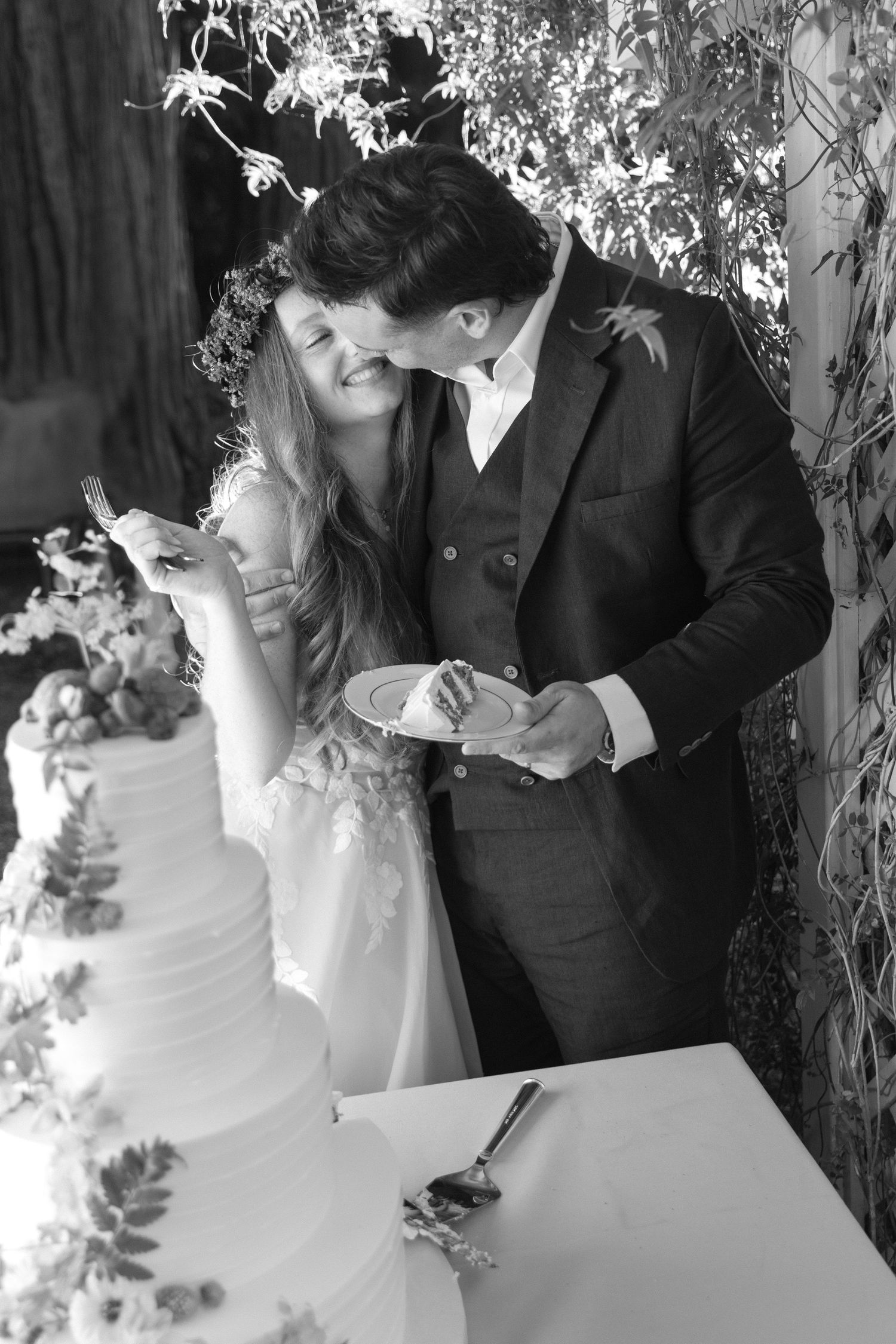 Black and white photos of a wedding couple cutting their multi-tiered cake together.