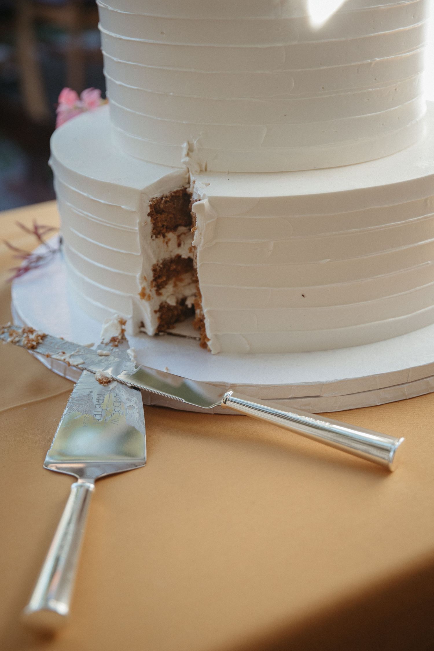 Close-up sequence showing a white wedding cake being cut with a silver serving knife.