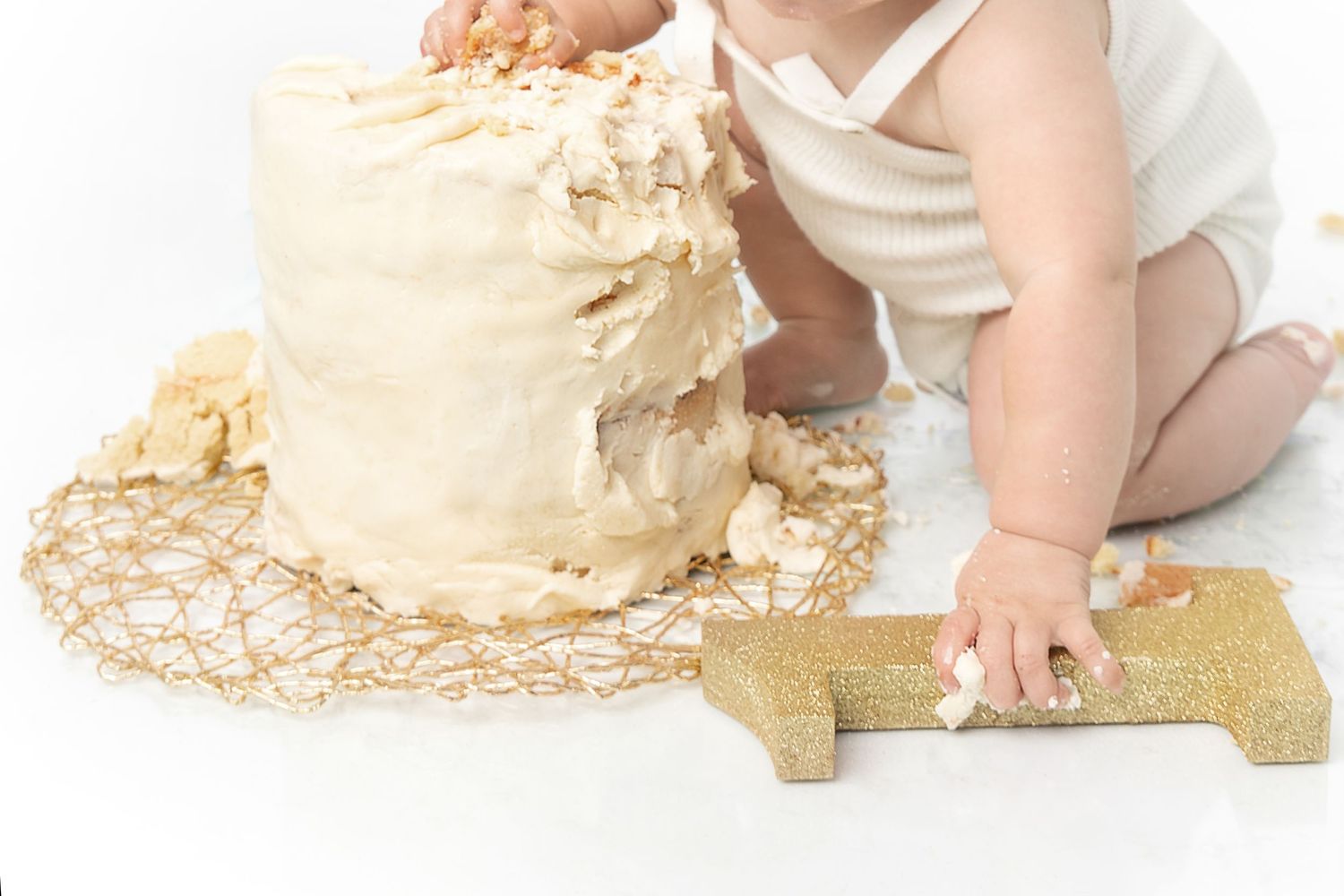 Close up of destroyed birthday cake with gold number one decoration.