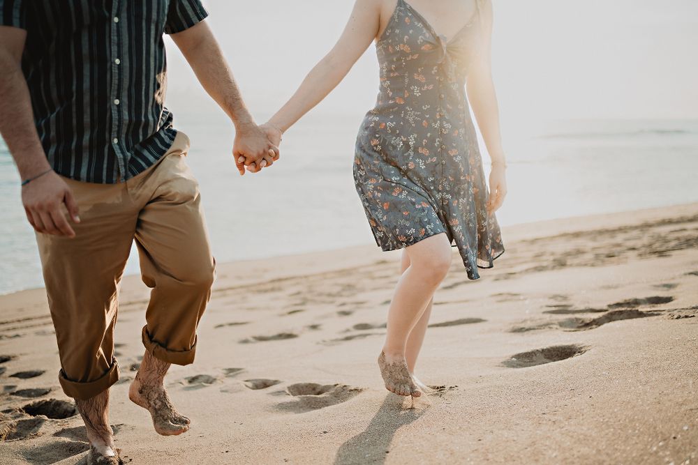 Paseo romántico por la orilla del mar en Mazatlán, pareja tomada de la mano.