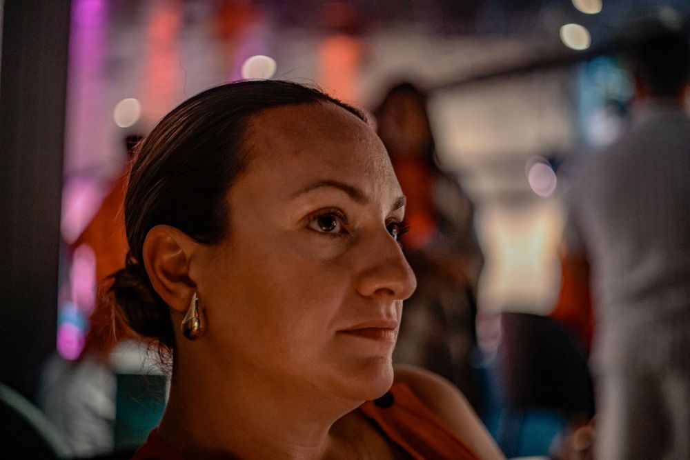 A contemplative portrait in low light with purple and pink ambient lighting.